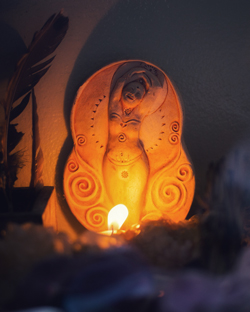 clay figure of a woman surrounded by candlelight representing fertility and creation showcasing six elements of harmony