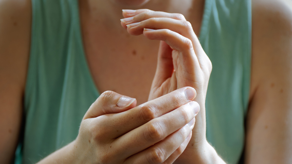 person gently touching hands indicating care and attention to two hands